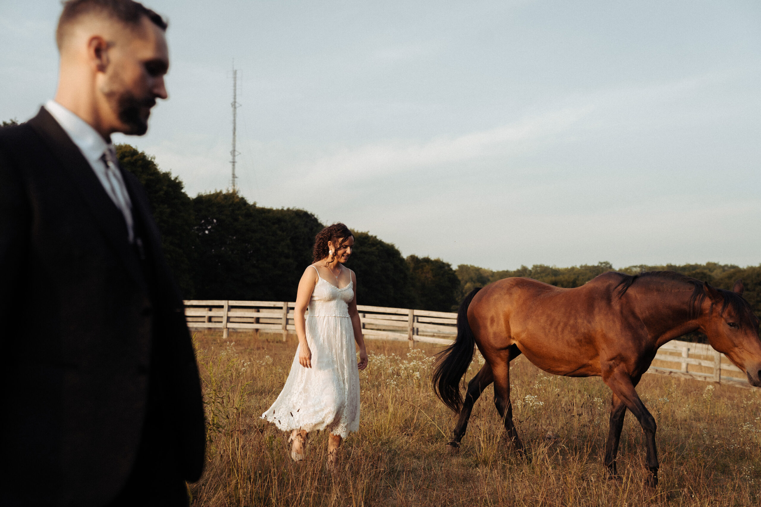 Bride and groom standing with their horses on their Aurora farm during sunset, rustic countryside wedding portraits.