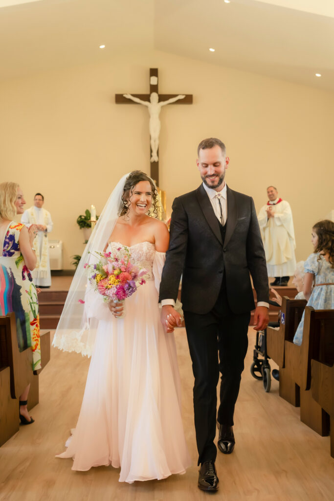 Courtney and John walking down the aisle at Our Lady of Grace Church in Aurora after their wedding ceremony.